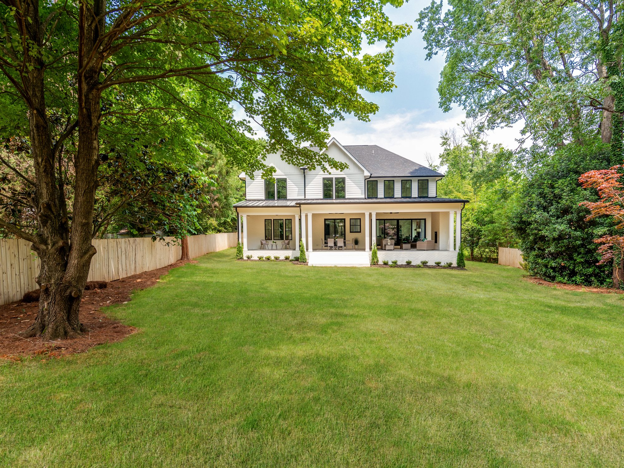 Brantham modern farmhouse front exterior framed by mature trees — Stillman Properties Charlotte NC