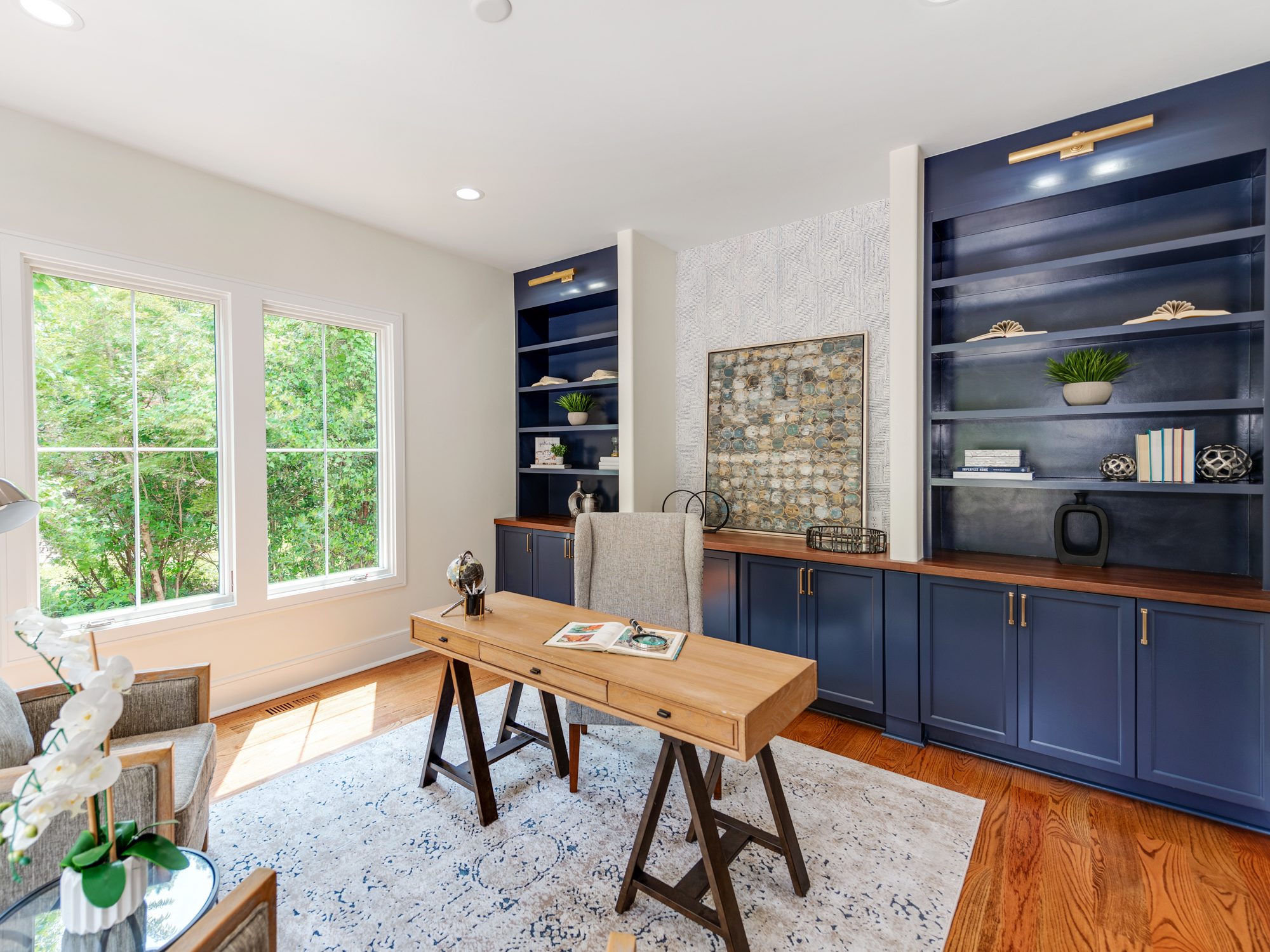 Office with deep navy built-in shelving and brass picture lights — Brantham by Stillman Properties Charlotte NC