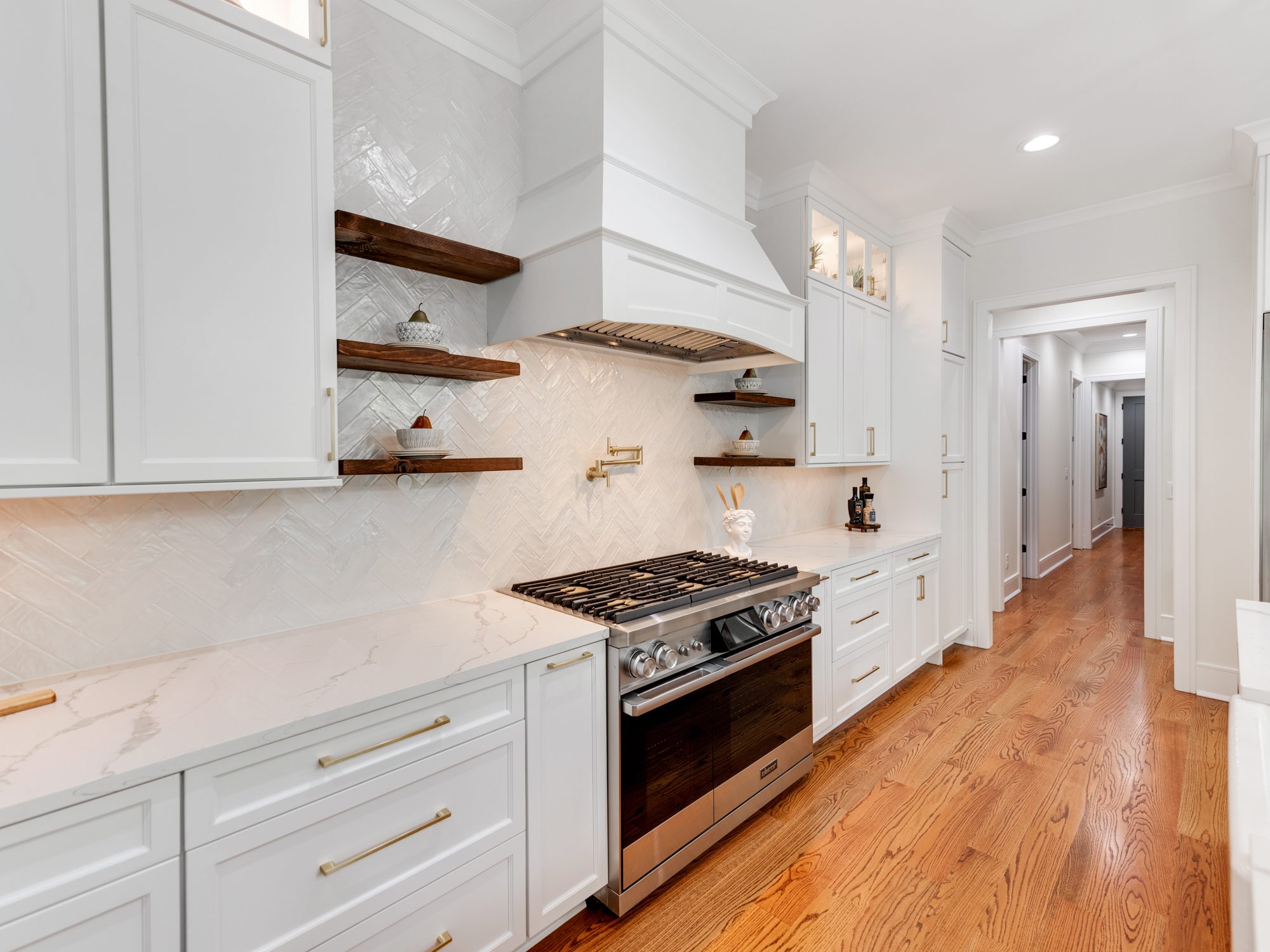 Kitchen range wall with pro-grade range, vent hood, and open shelving — Brantham by Stillman Properties Charlotte NC