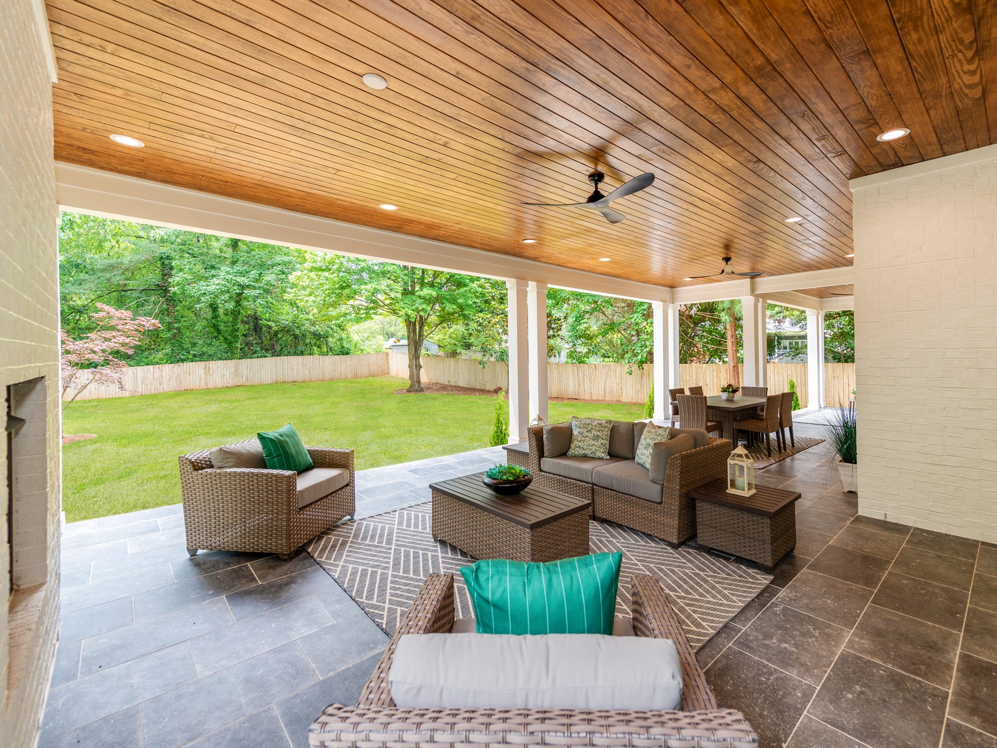 Covered outdoor living room with stone fireplace and woven sectional — Brantham by Stillman Properties Charlotte NC