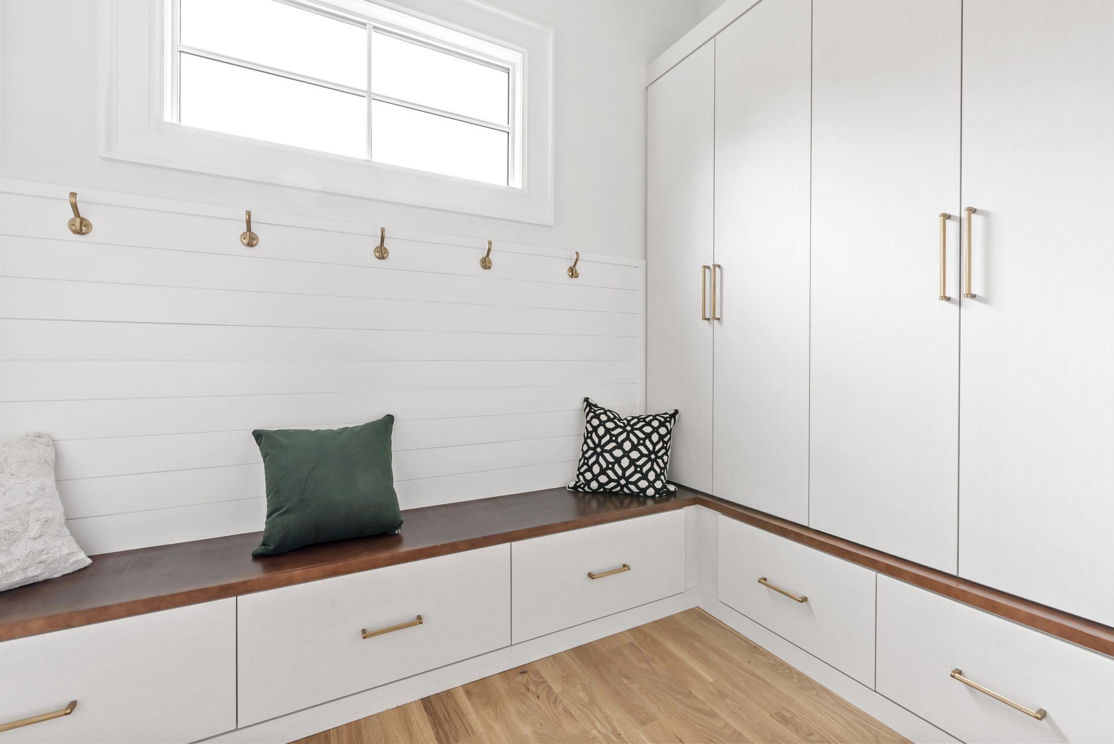 Mudroom with built-in bench, brass hooks, and full-height lockers — Bywood by Stillman Properties Charlotte NC