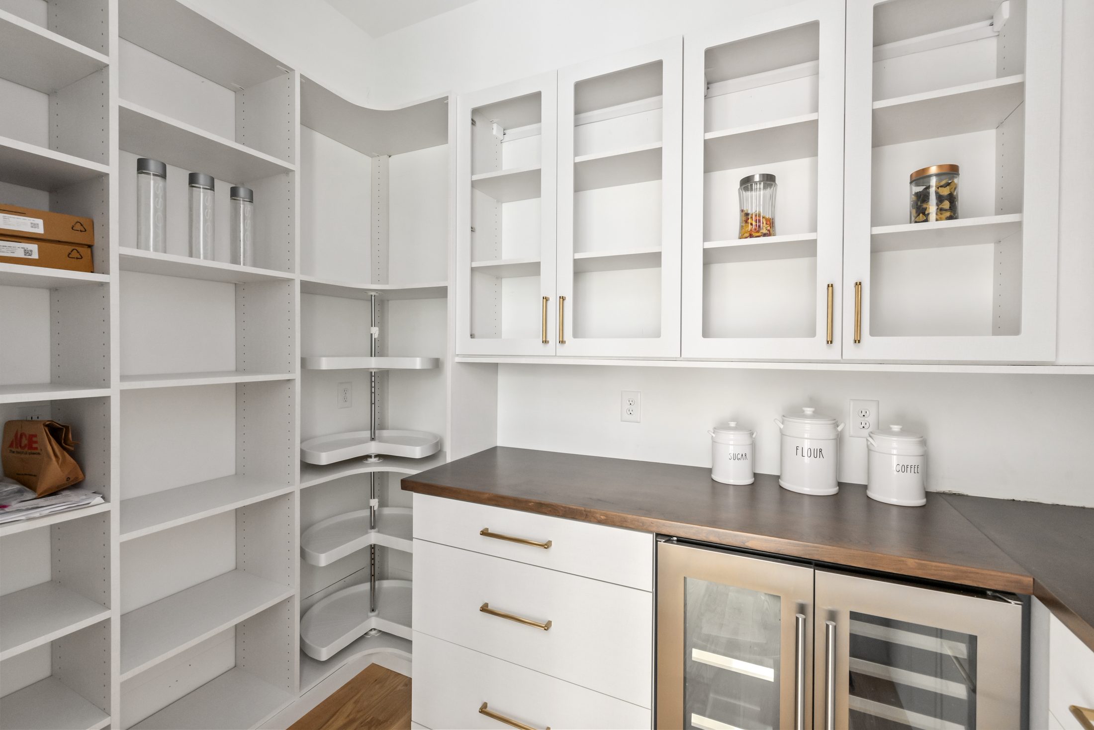 Walk-in pantry with custom white shelving, corner carousel, butcher-block counter, and beverage center — Bywood by Stillman Properties Charlotte NC