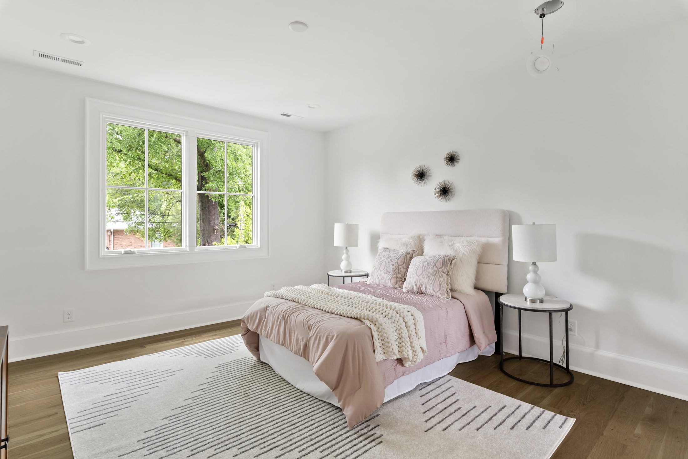 Secondary bedroom with blush bedding and treetop window views — Bywood by Stillman Properties Charlotte NC
