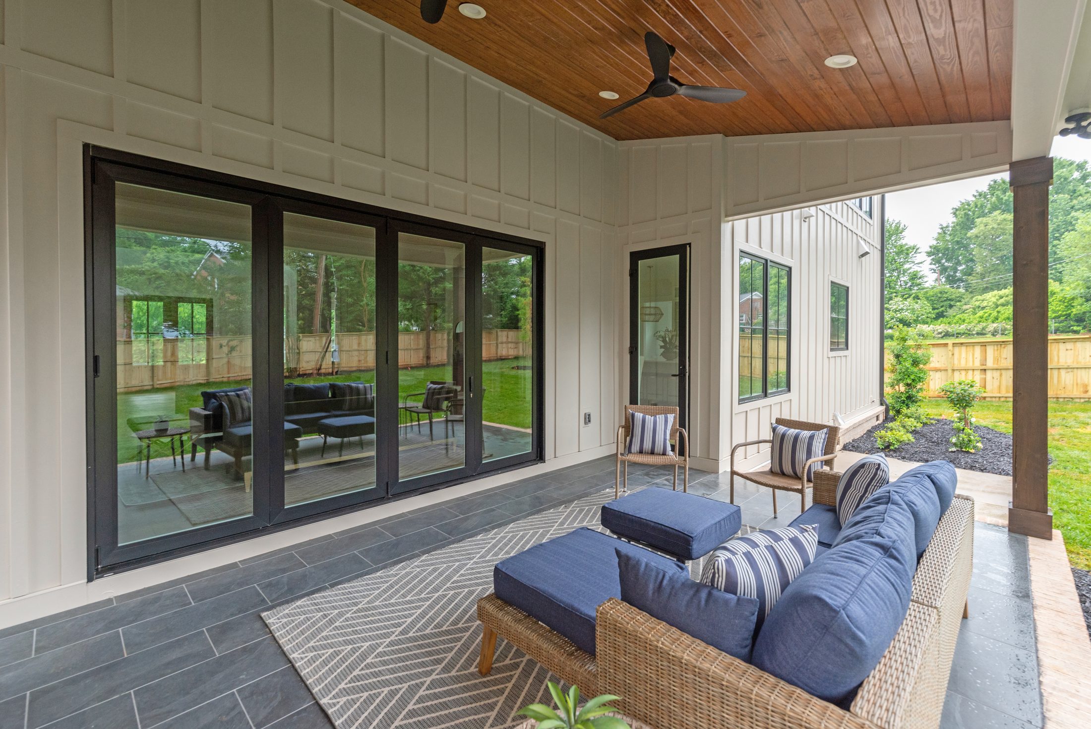 Covered porch with floor-to-ceiling sliding glass doors connecting the outdoor living room to the interior — Bywood by Stillman Properties Charlotte NC