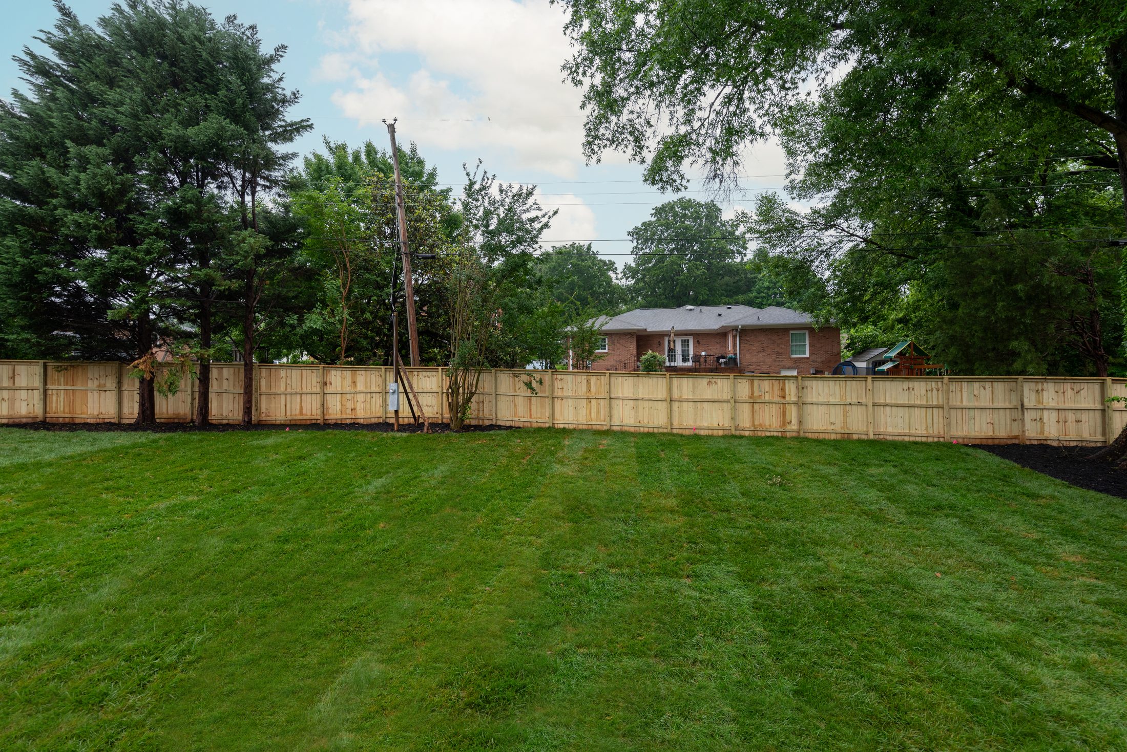 Fully fenced backyard with mature tree line and freshly planted trees — Bywood by Stillman Properties Charlotte NC