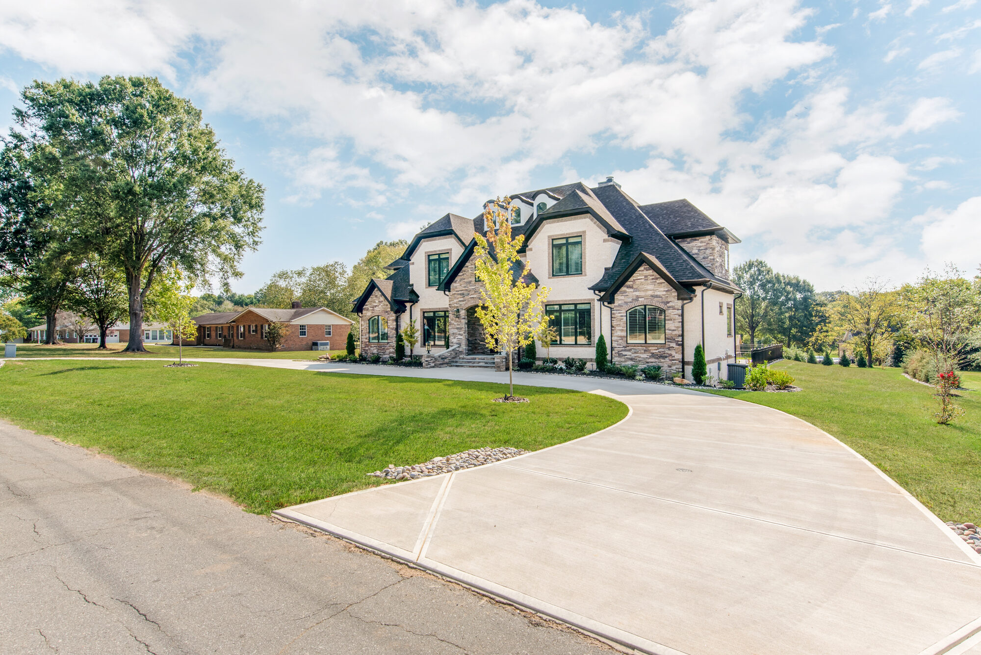 Coddle Creek custom estate home — front driveway angle showing stone and brick façade with deep eaves — Stillman Properties Concord NC