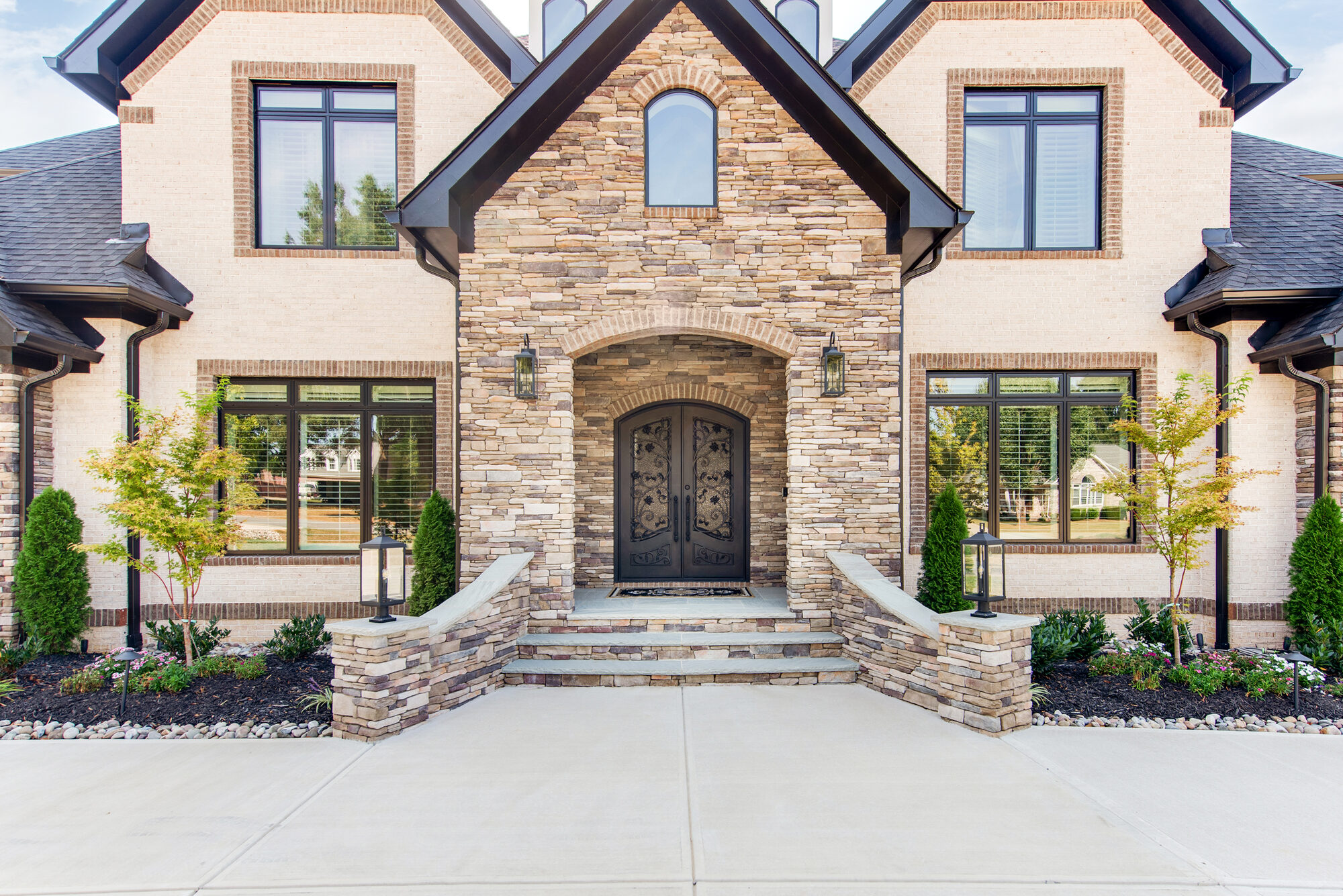Front entry detail of Coddle Creek with stacked stone surround, arched iron doors, and copper lanterns — Stillman Properties Concord NC