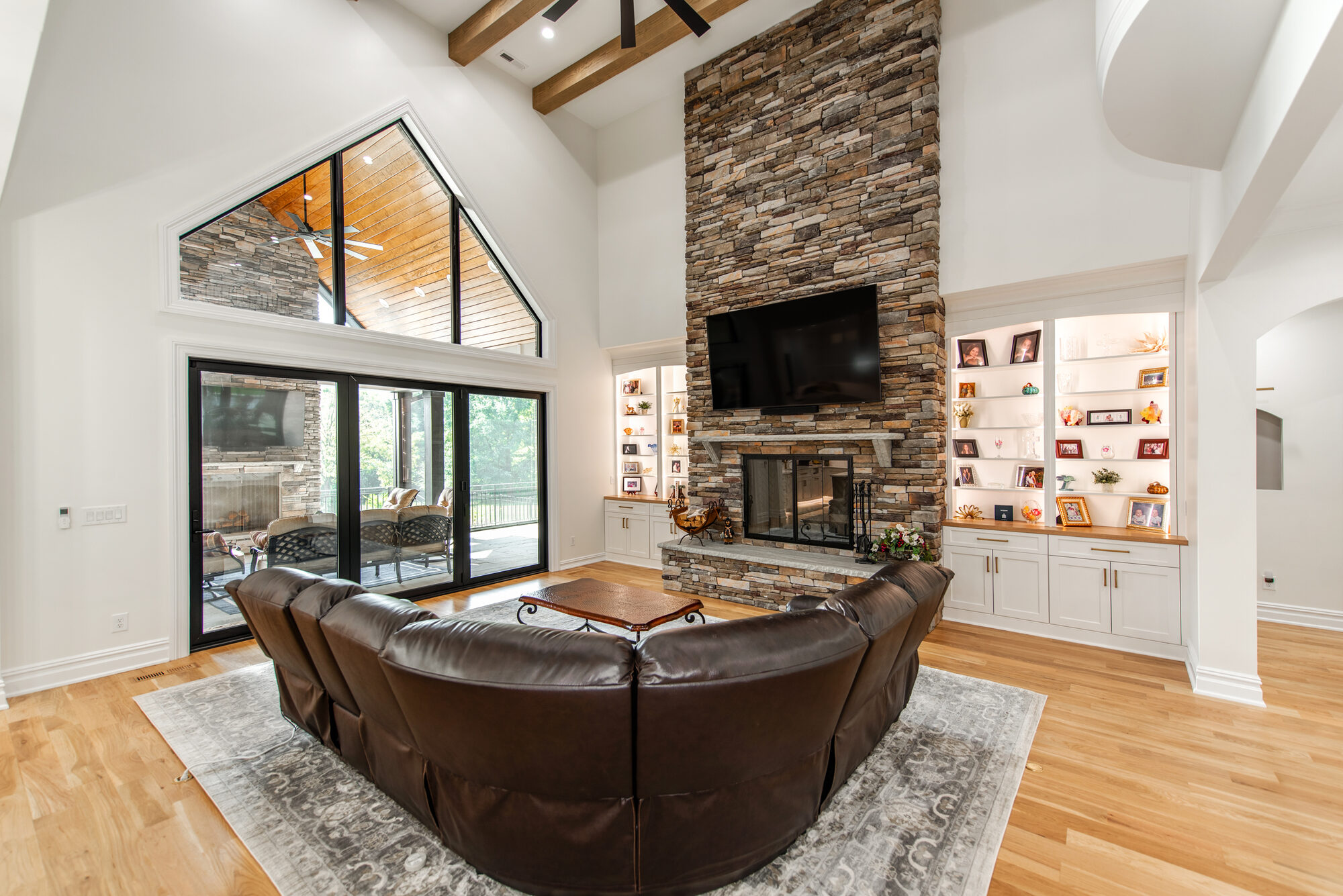 Vaulted great room with floor-to-ceiling stacked stone fireplace, exposed beams, and flanking built-ins — Coddle Creek by Stillman Properties Concord NC