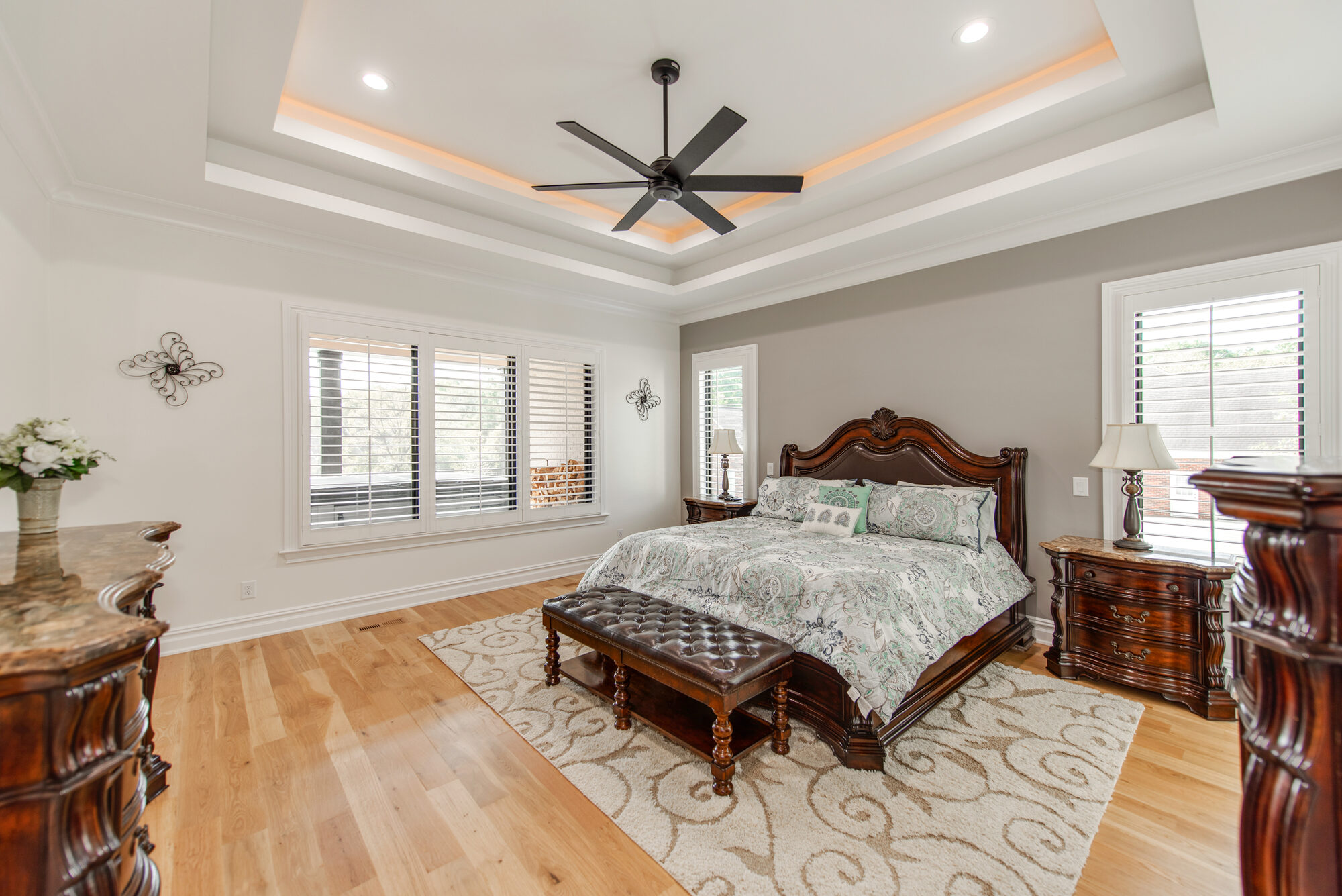 Primary bedroom with double tray ceiling, recessed cove lighting, and bay-window seating area — Coddle Creek by Stillman Properties Concord NC