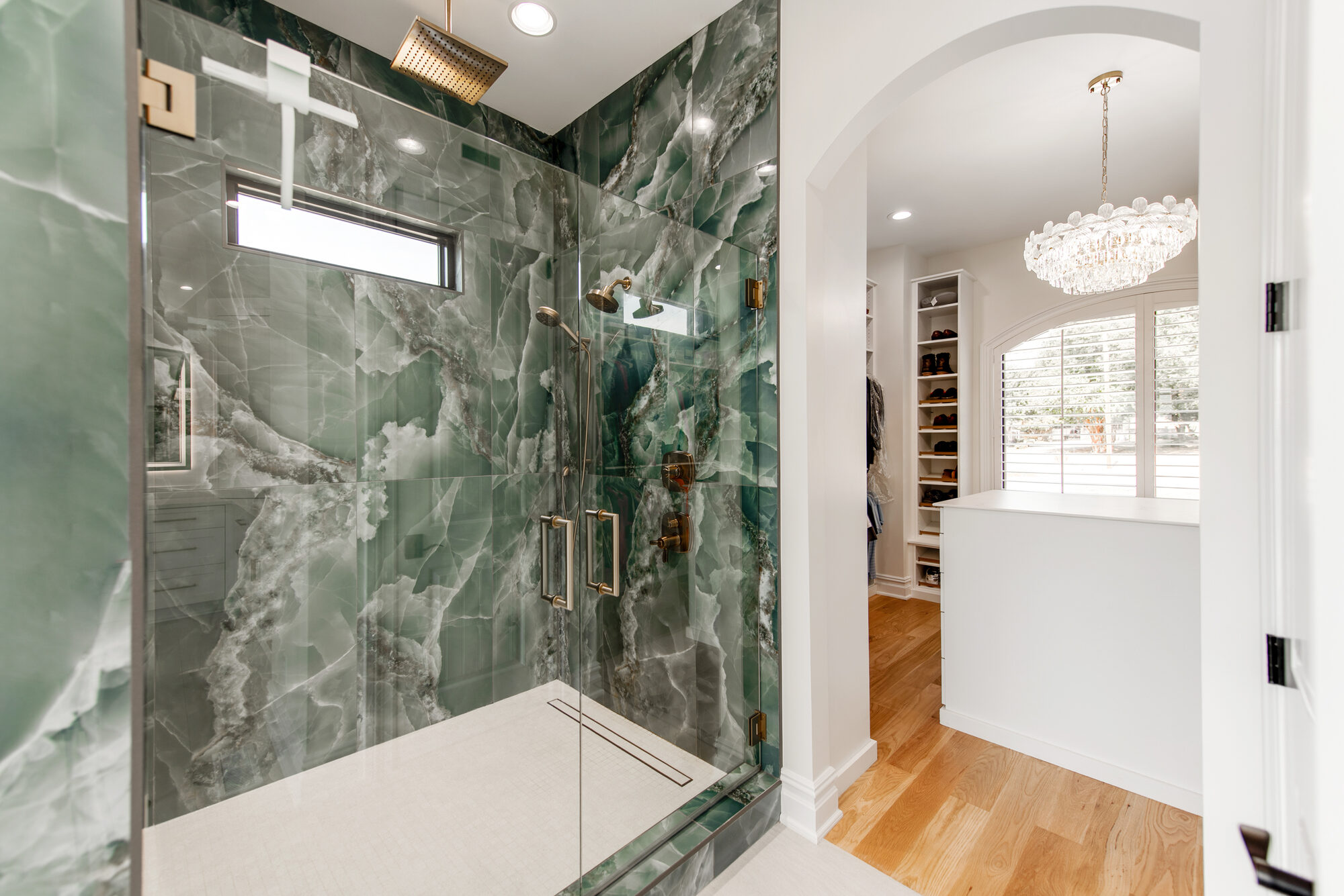 Green onyx walk-in shower with brass rainhead and view through to the custom closet — Coddle Creek by Stillman Properties Concord NC