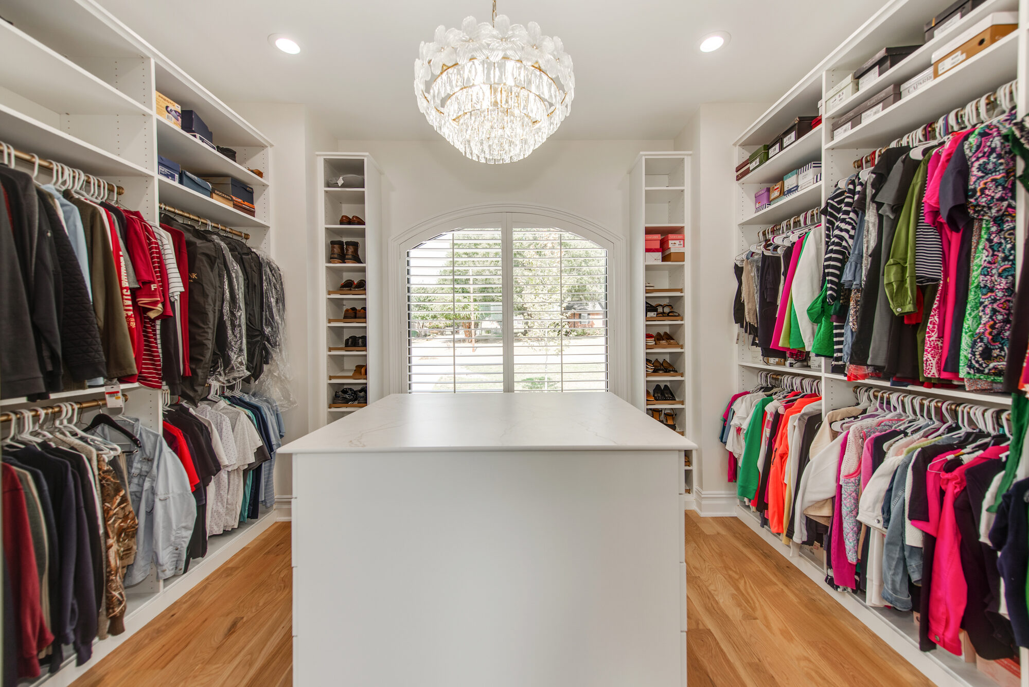 Custom primary closet with quartz-topped center island, crystal chandelier, and shoe display — Coddle Creek by Stillman Properties Concord NC