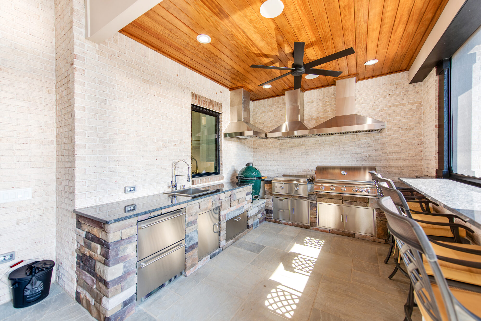 Outdoor kitchen detail with stainless dual hoods, Wolf gas grill, Big Green Egg, and bar seating — Coddle Creek by Stillman Properties Concord NC