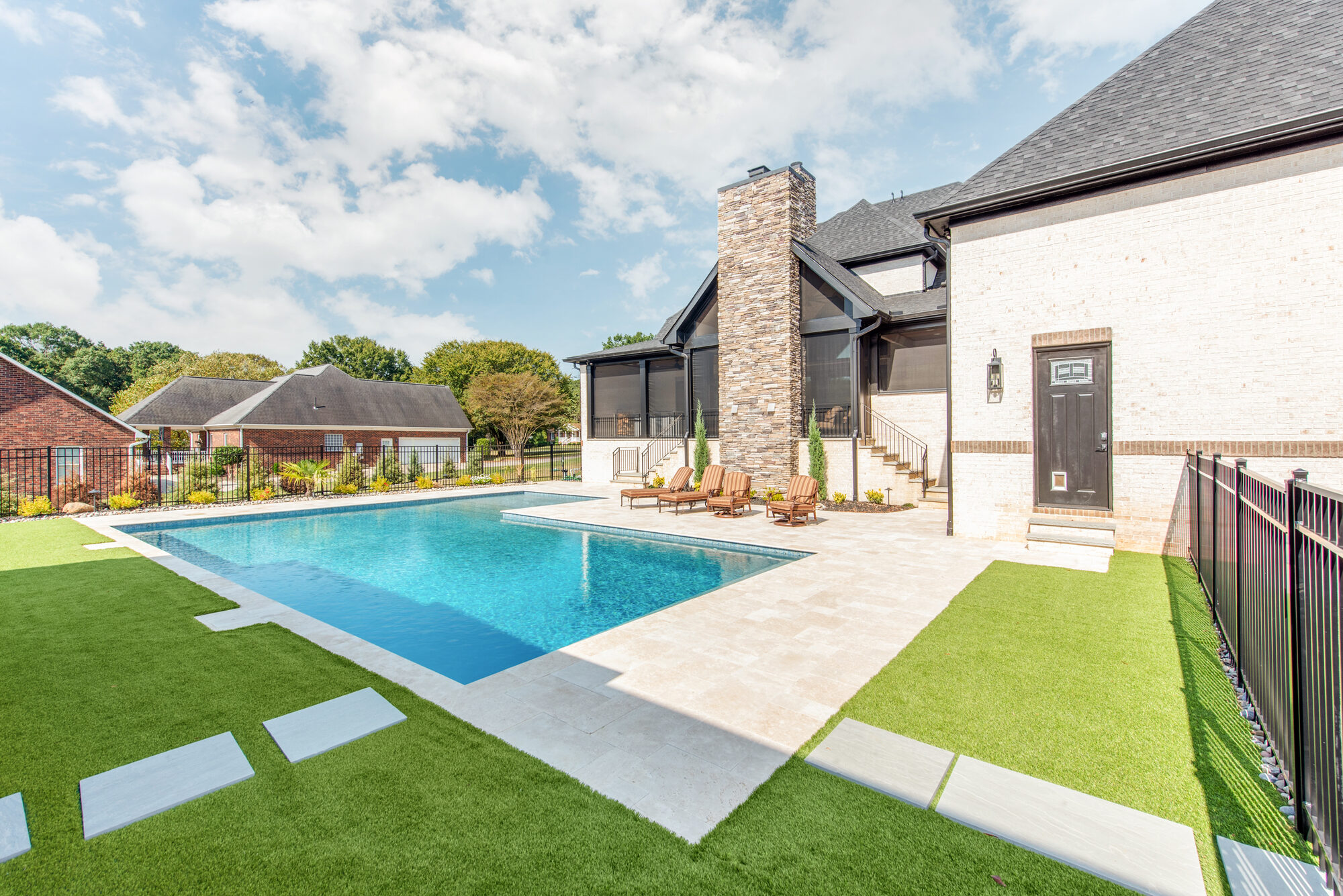 Travertine pool deck with chaise loungers and screened porch beyond — Coddle Creek by Stillman Properties Concord NC