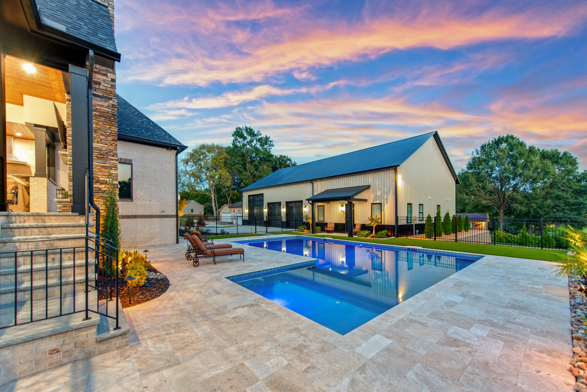 Twilight view of Coddle Creek showing the illuminated main residence and barndominium against a sunset sky — Stillman Properties Concord NC