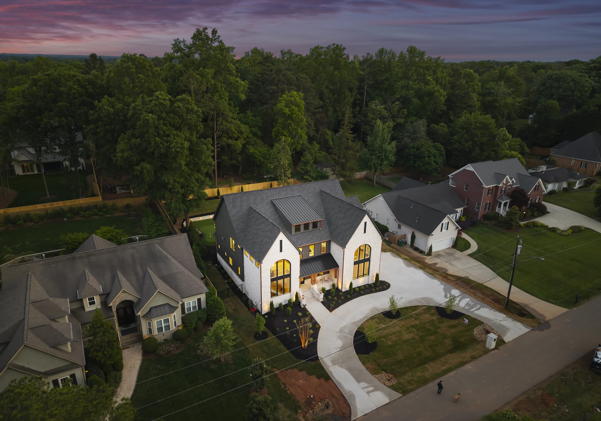 Aerial twilight view of Creola custom home in Charlotte NC by Stillman Properties — warm interior glow at dusk