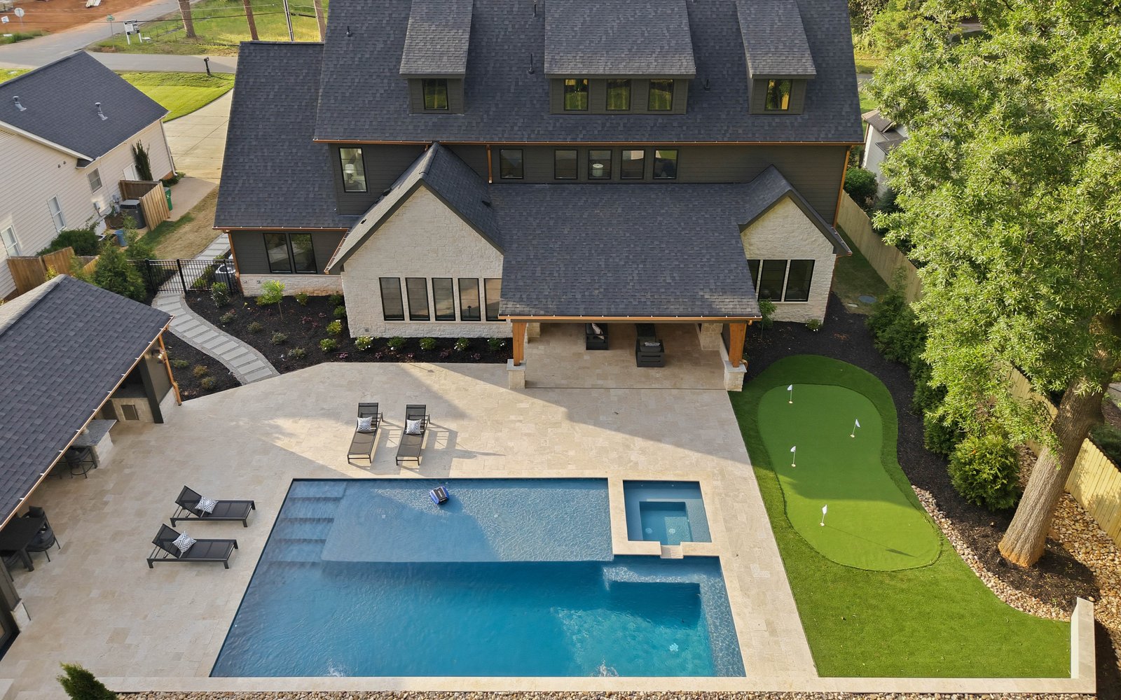 Aerial twilight view of the rear of Creola showing pool, putting green, cabana, and travertine deck — Creola custom home in Charlotte NC by Stillman Properties