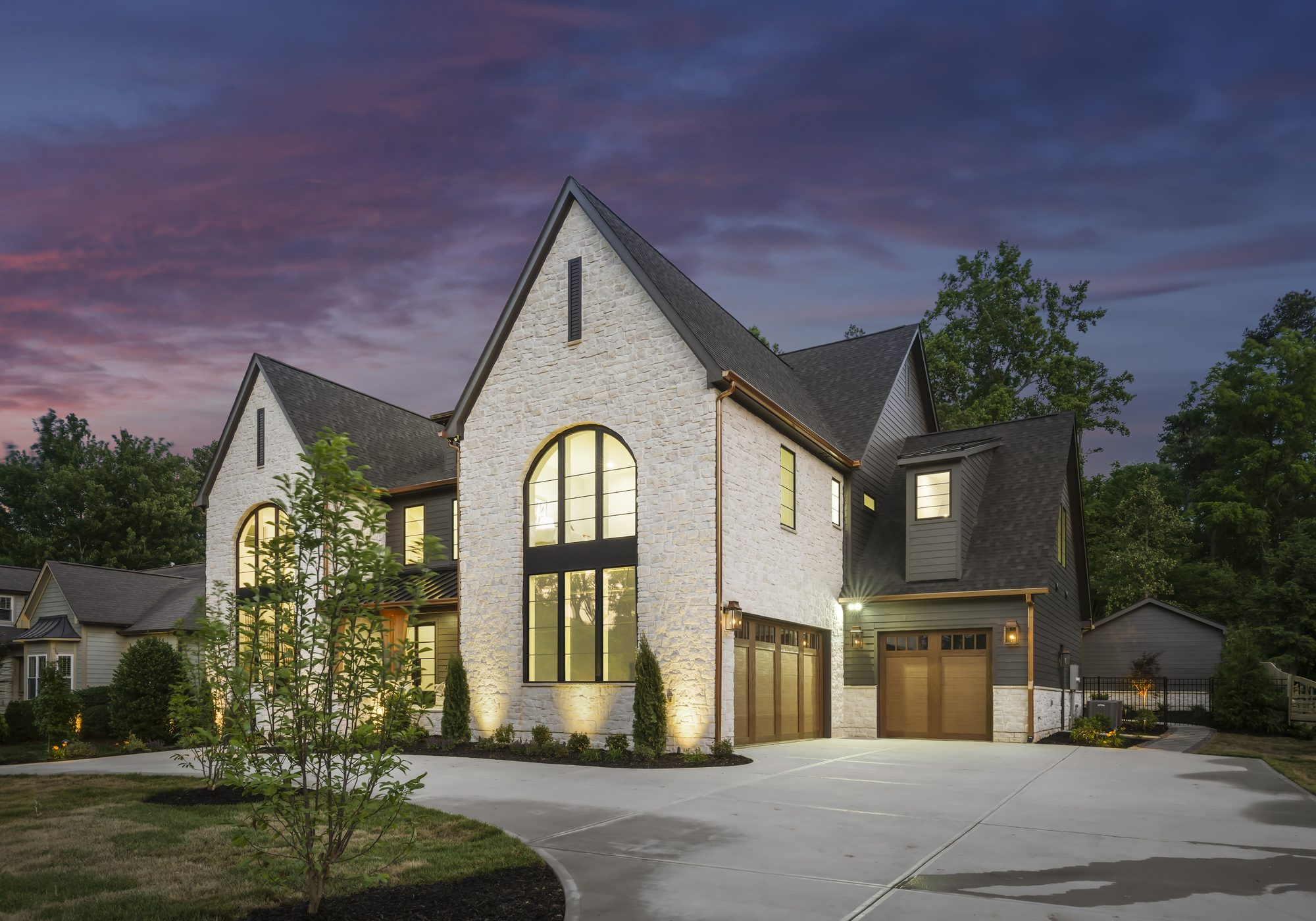 Three-quarter view of Creola at twilight showing limestone gables and garage — Creola custom home in Charlotte NC by Stillman Properties