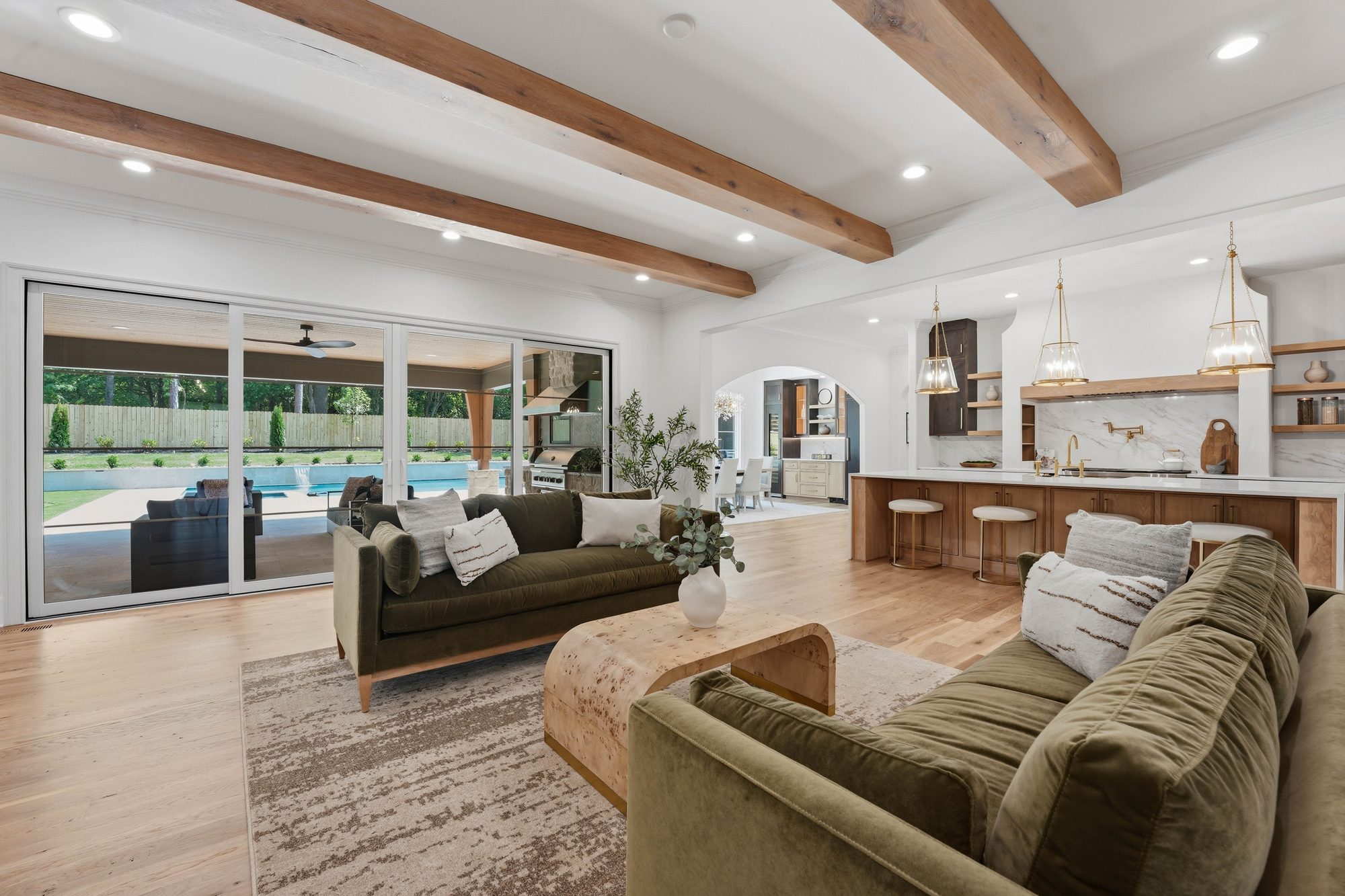 Great room with hand-hewn ceiling beams opening to kitchen and pool — Creola custom home in Charlotte NC by Stillman Properties