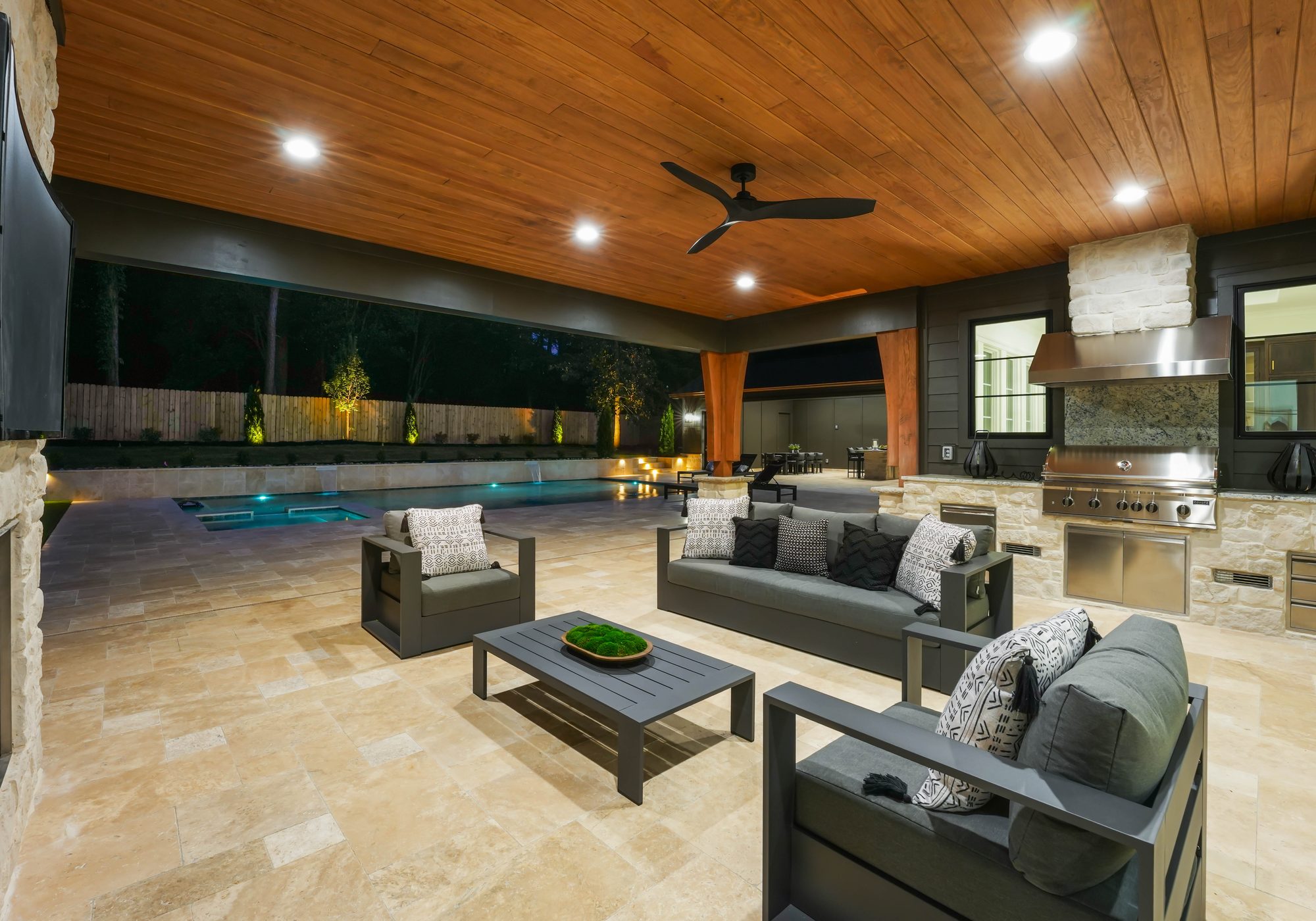 Covered outdoor living room at twilight with stone fireplace and wood-clad ceiling — Creola custom home in Charlotte NC by Stillman Properties