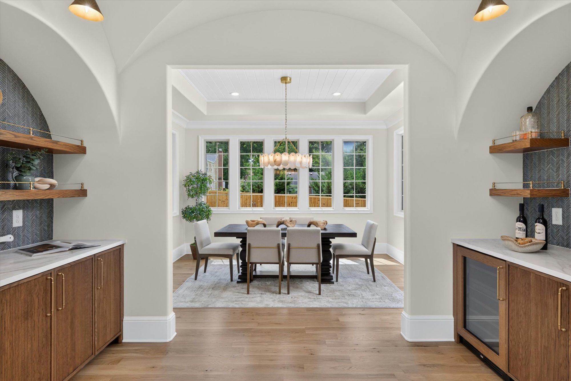 Paired groin-vaulted arches at Heather framing the dining room beyond, with fluted oak cabinetry and marble counters on either side — Heather by Stillman Properties Charlotte NC