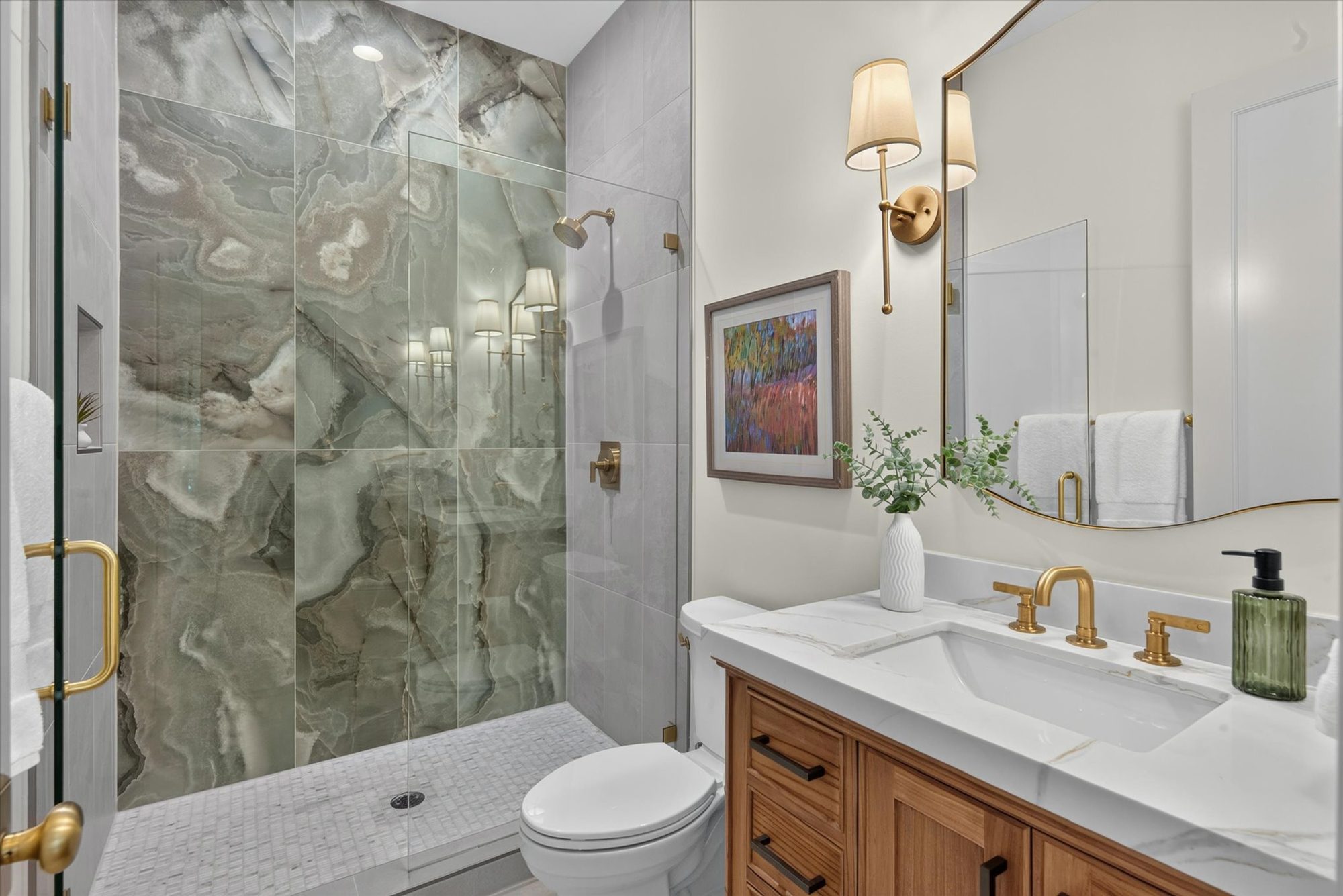 Full bath adjacent to the main-level guest/office at Heather, with a green onyx-veined shower slab, brass sconces, and a wood vanity with marble top — Heather by Stillman Properties Charlotte NC