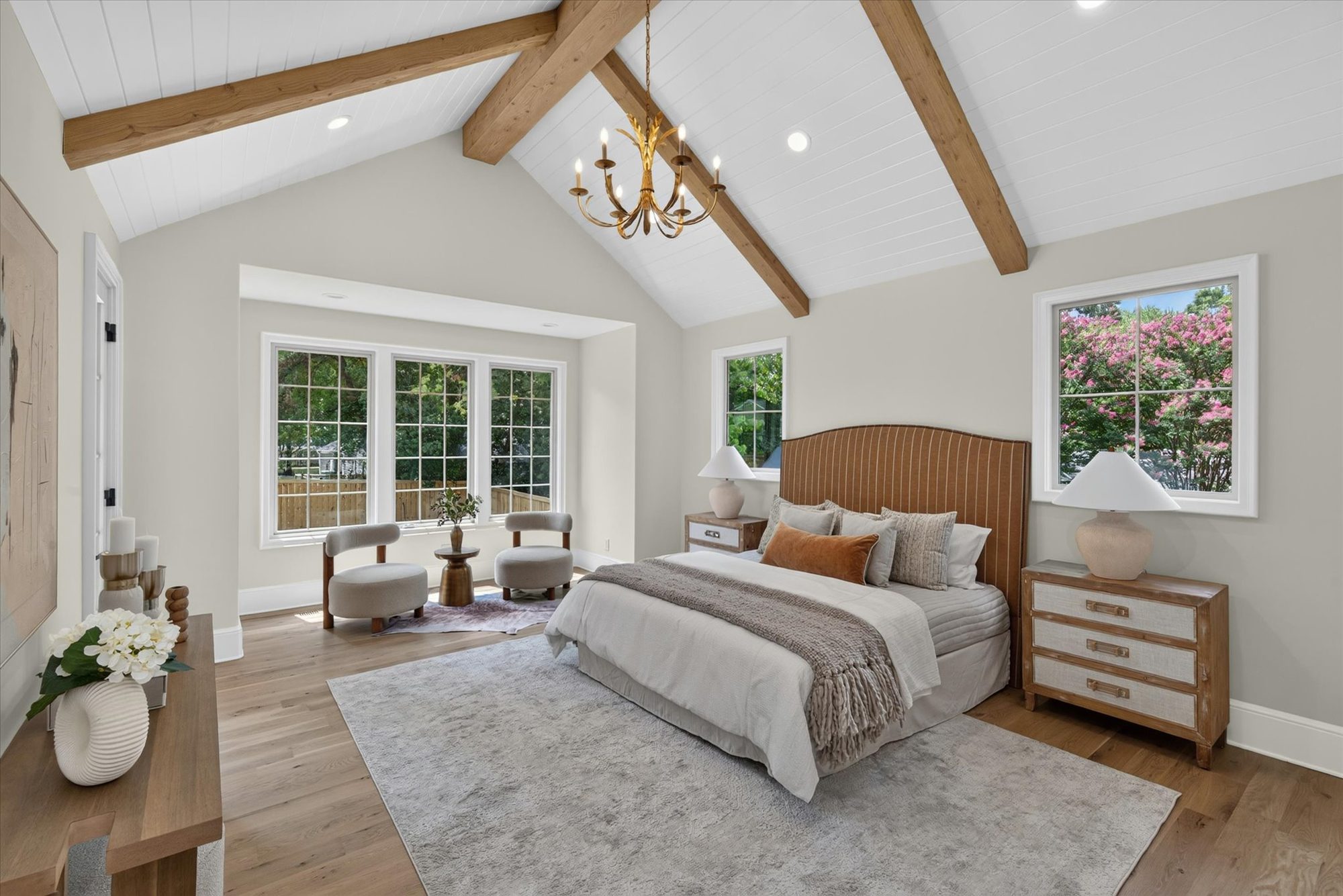 Main-level primary suite at Heather with vaulted white shiplap ceiling, stained beams, brass chandelier, and bay-window sitting area — Heather by Stillman Properties Charlotte NC
