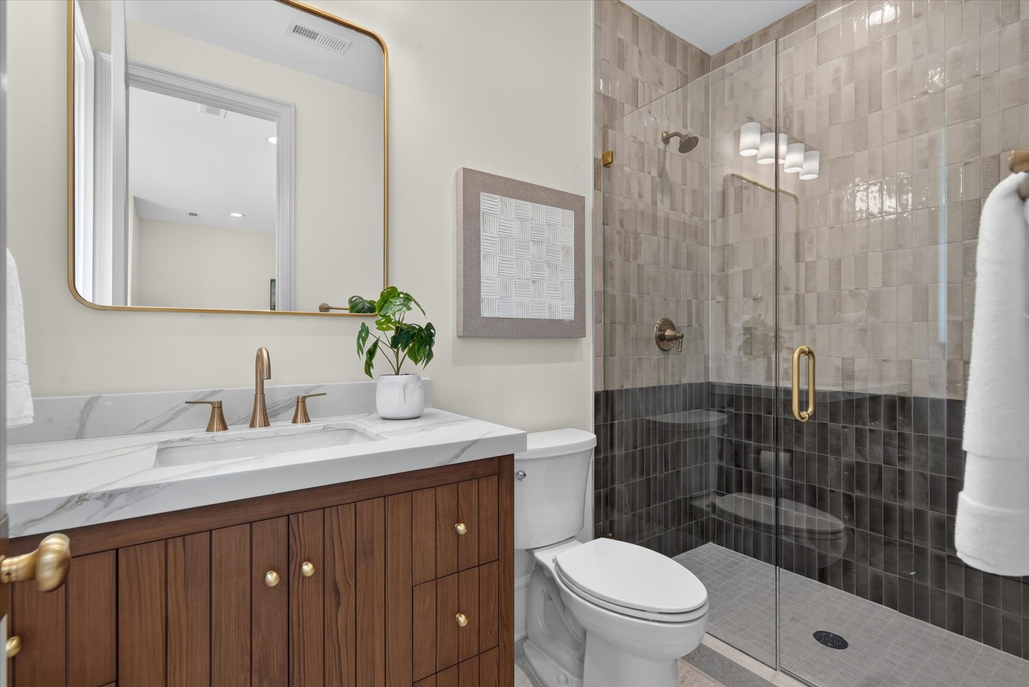 Bath at Heather with fluted walnut vanity, marble top, brass hardware, and a two-tone glazed tile shower — Heather by Stillman Properties Charlotte NC
