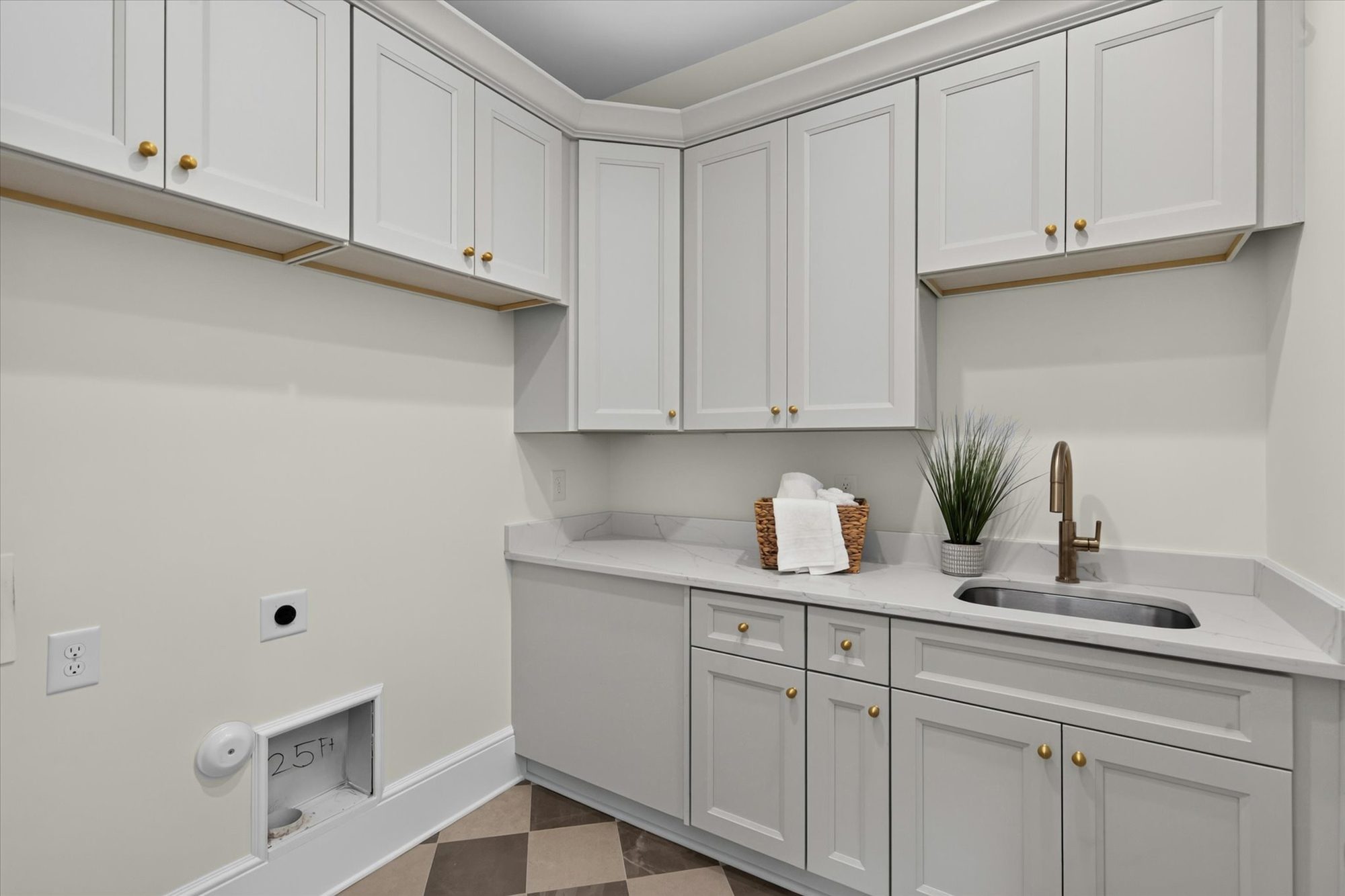 Second-floor laundry room at Heather with white cabinetry, quartz counters, utility sink, and checkerboard tile floor — Heather by Stillman Properties Charlotte NC