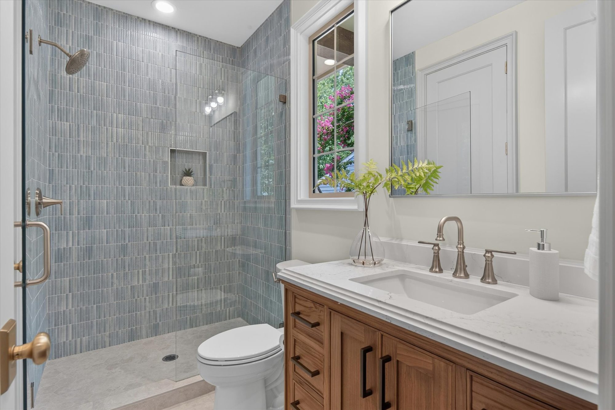 Bath at Heather with a walk-in shower in stacked blue-green tile, wood vanity, and marble counter — Heather by Stillman Properties Charlotte NC