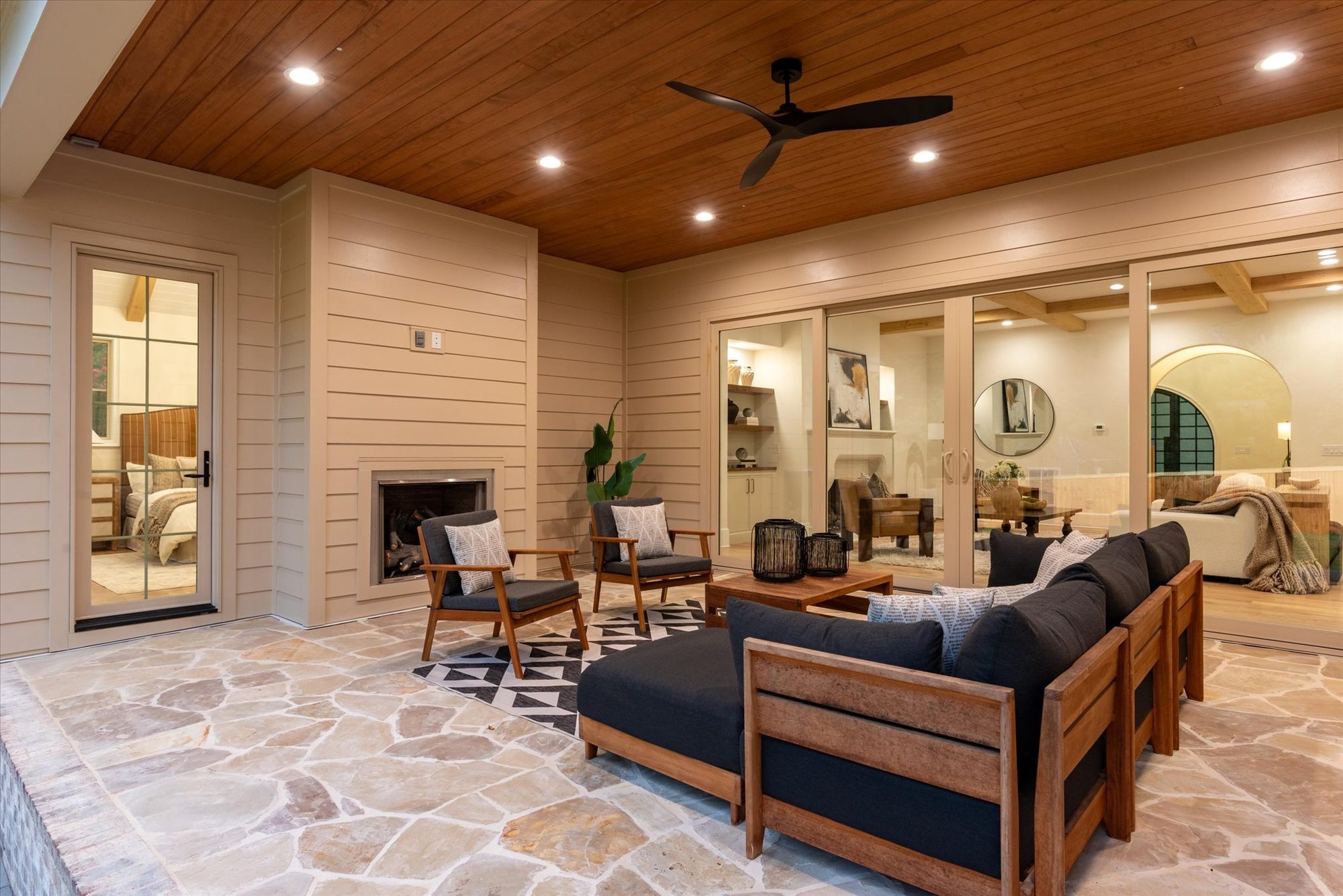 Covered porch at Heather with cedar plank ceiling, outdoor fireplace, flagstone floor, and sliders to the great room and primary suite — Heather by Stillman Properties Charlotte NC