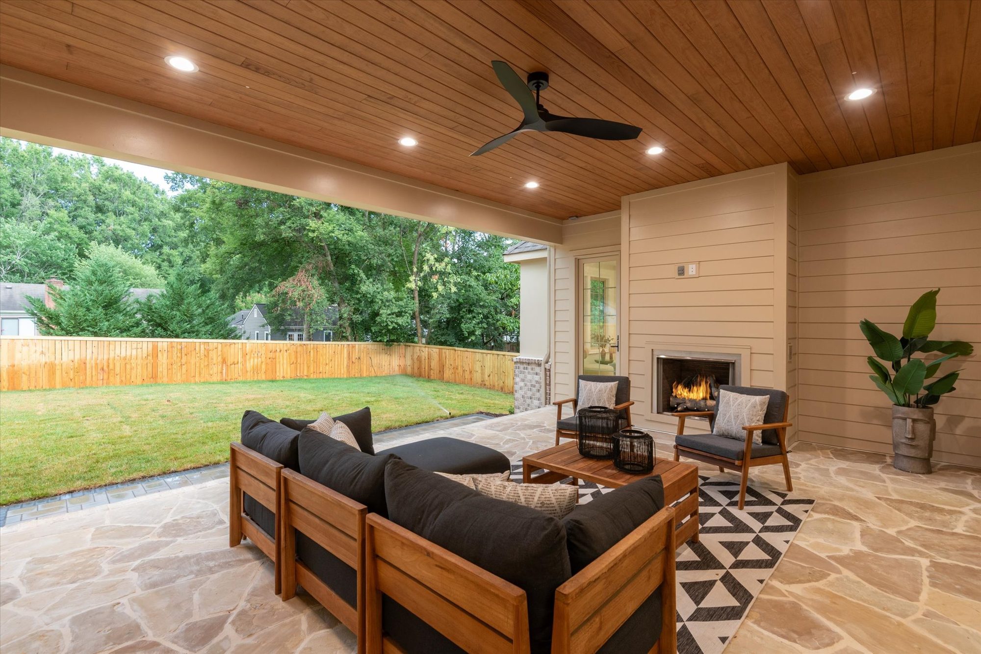 Covered porch at Heather with fireplace lit, looking out over the fenced rear lawn — Heather by Stillman Properties Charlotte NC