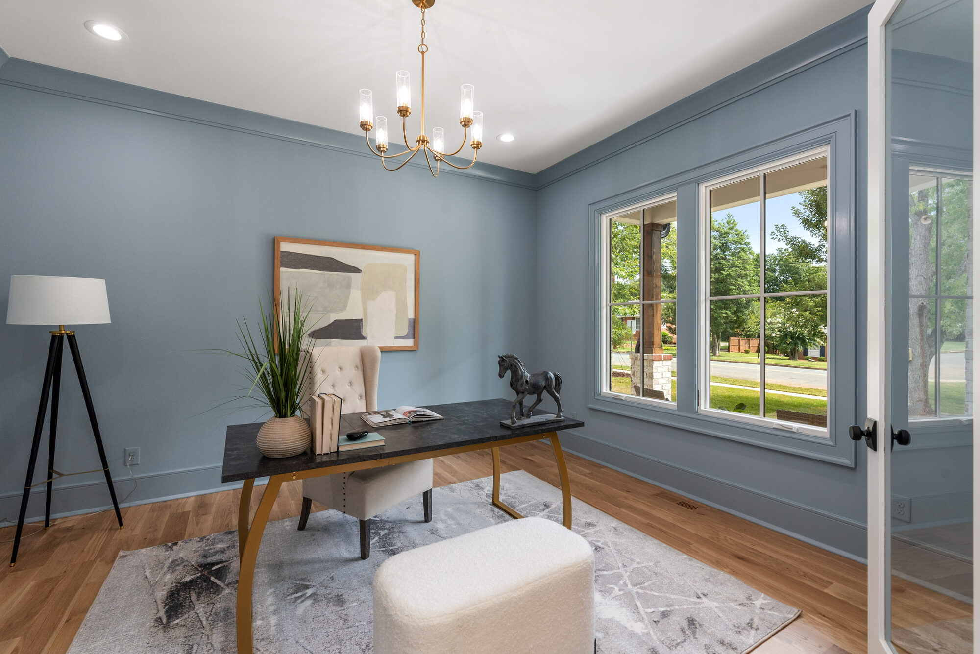 Walker home office with deep blue walls, brass candelabra chandelier, and picture-window view — Stillman Properties Cotswold Charlotte NC