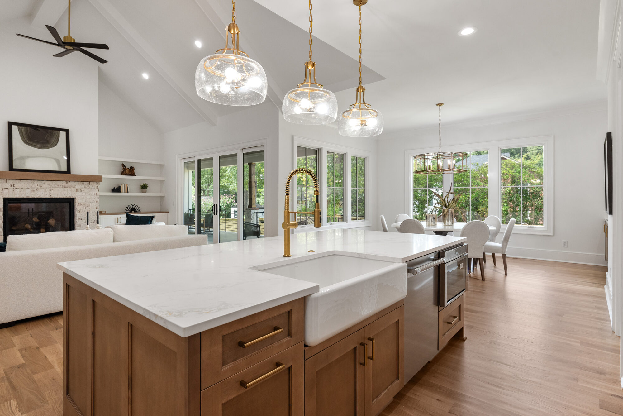 Walker kitchen island farmhouse sink with brass spring faucet and sightlines to the breakfast room — Stillman Properties Cotswold Charlotte NC