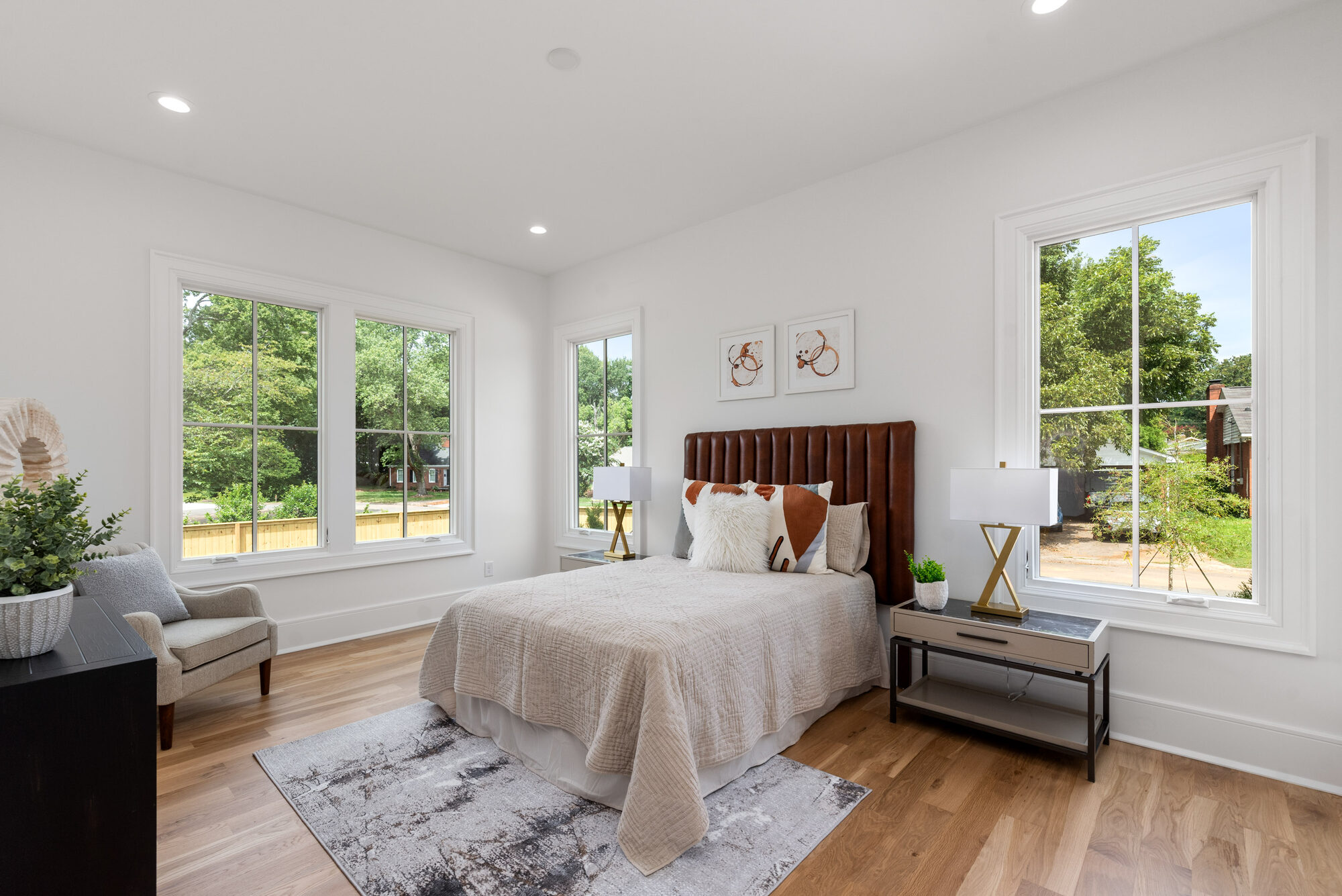 Walker guest bedroom with leather channel-tufted headboard and three-window corner light — Stillman Properties Cotswold Charlotte NC