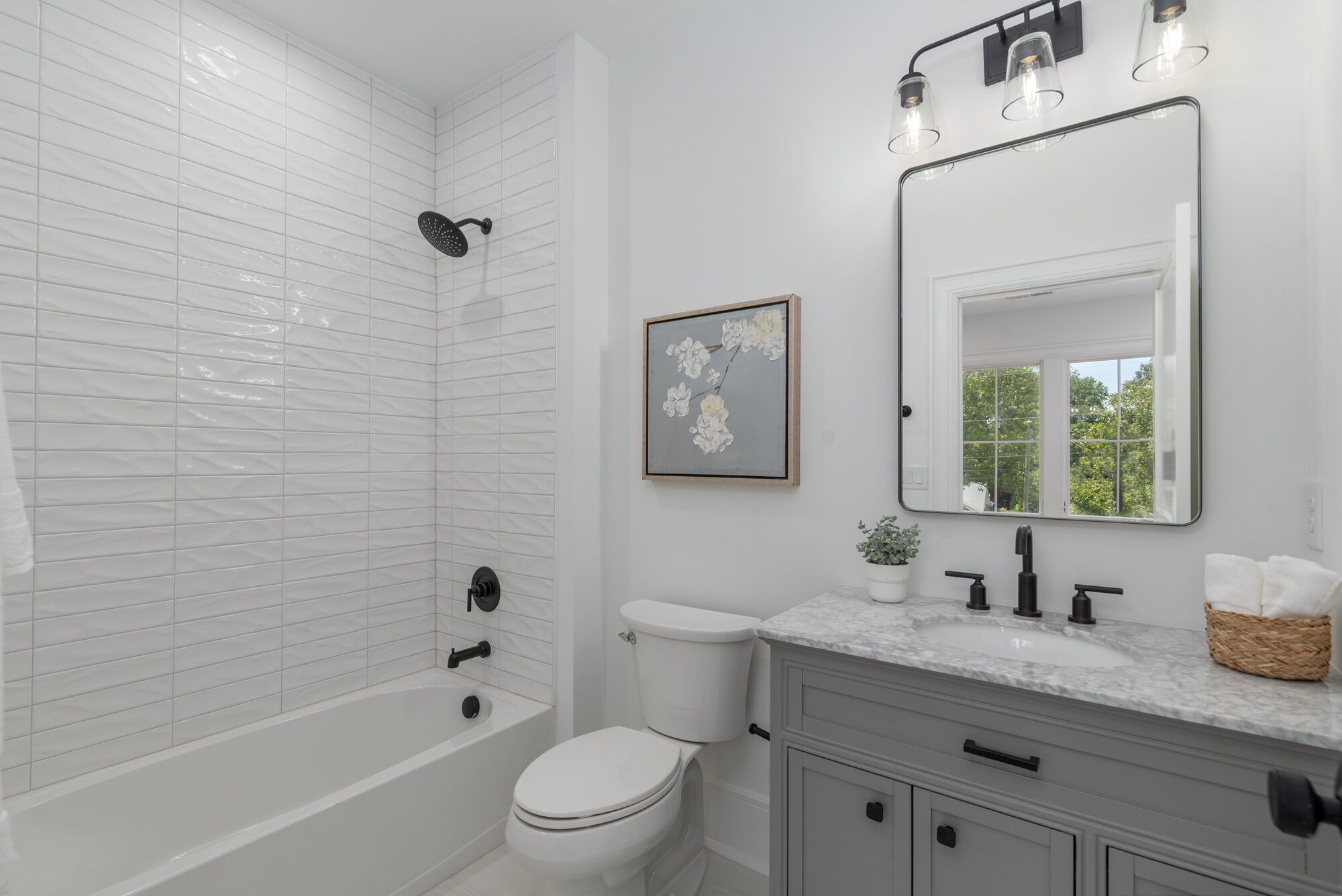Walker guest bath with stacked tile tub surround, marble vanity, and matte black hardware — Stillman Properties Cotswold Charlotte NC