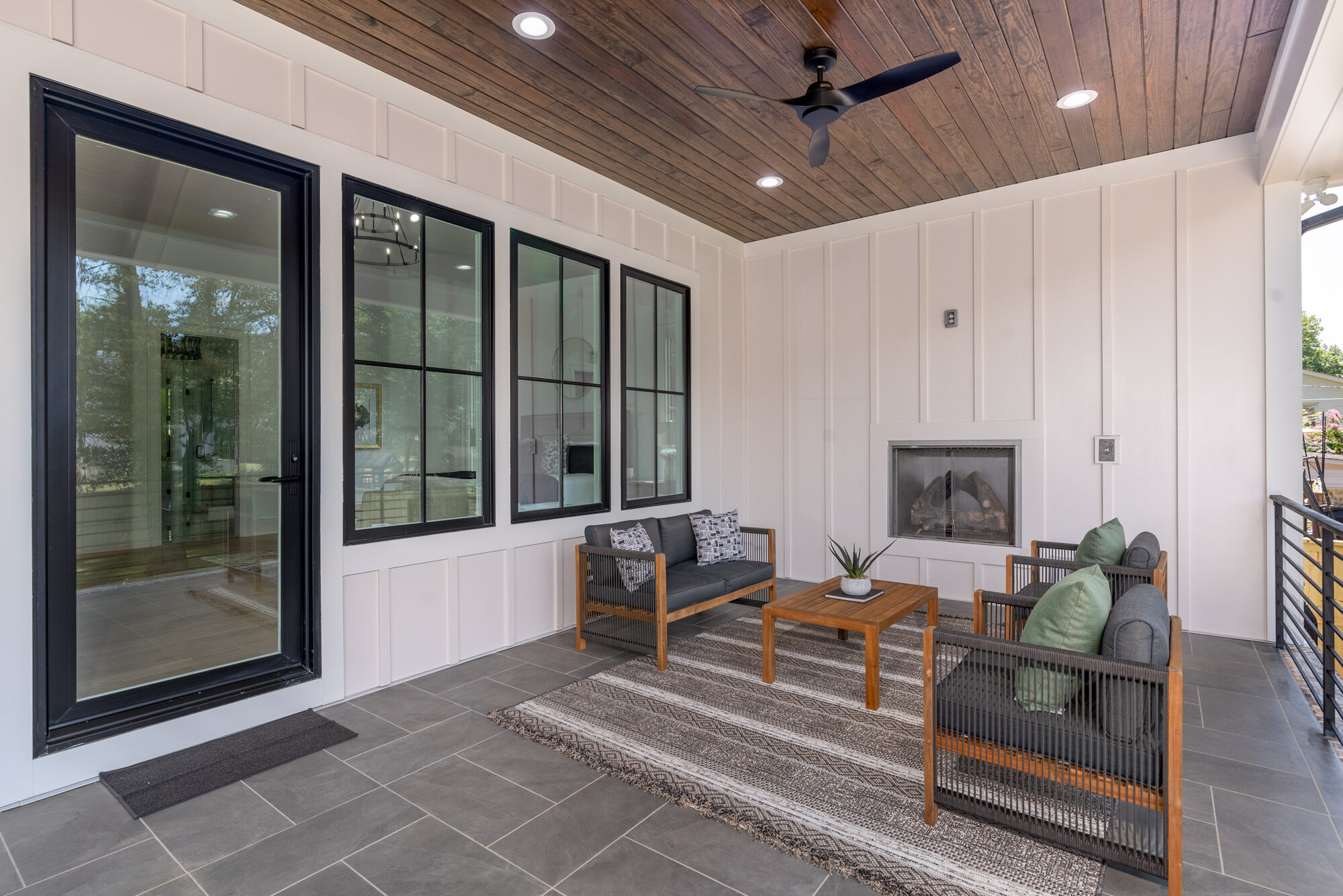 Walker covered deck seating area with outdoor fireplace and steel-framed windows looking into the great room — Stillman Properties Cotswold Charlotte NC