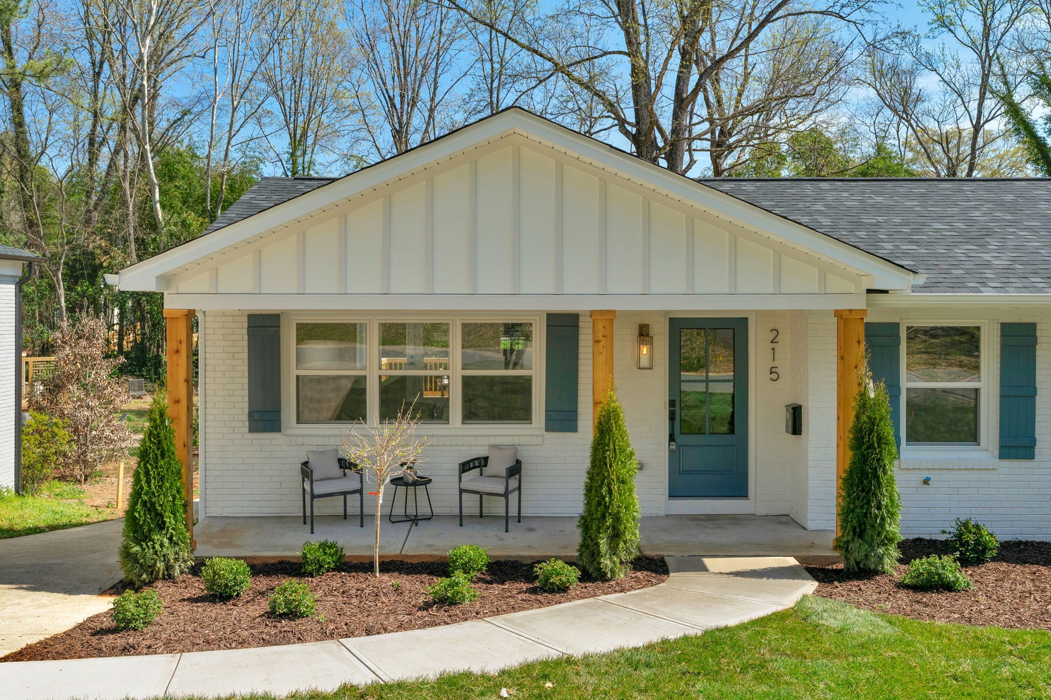 Wyanoke full home renovation in Chantilly, Charlotte NC by Stillman Properties — renovated ranch front elevation with board-and-batten siding and a cedar-post porch