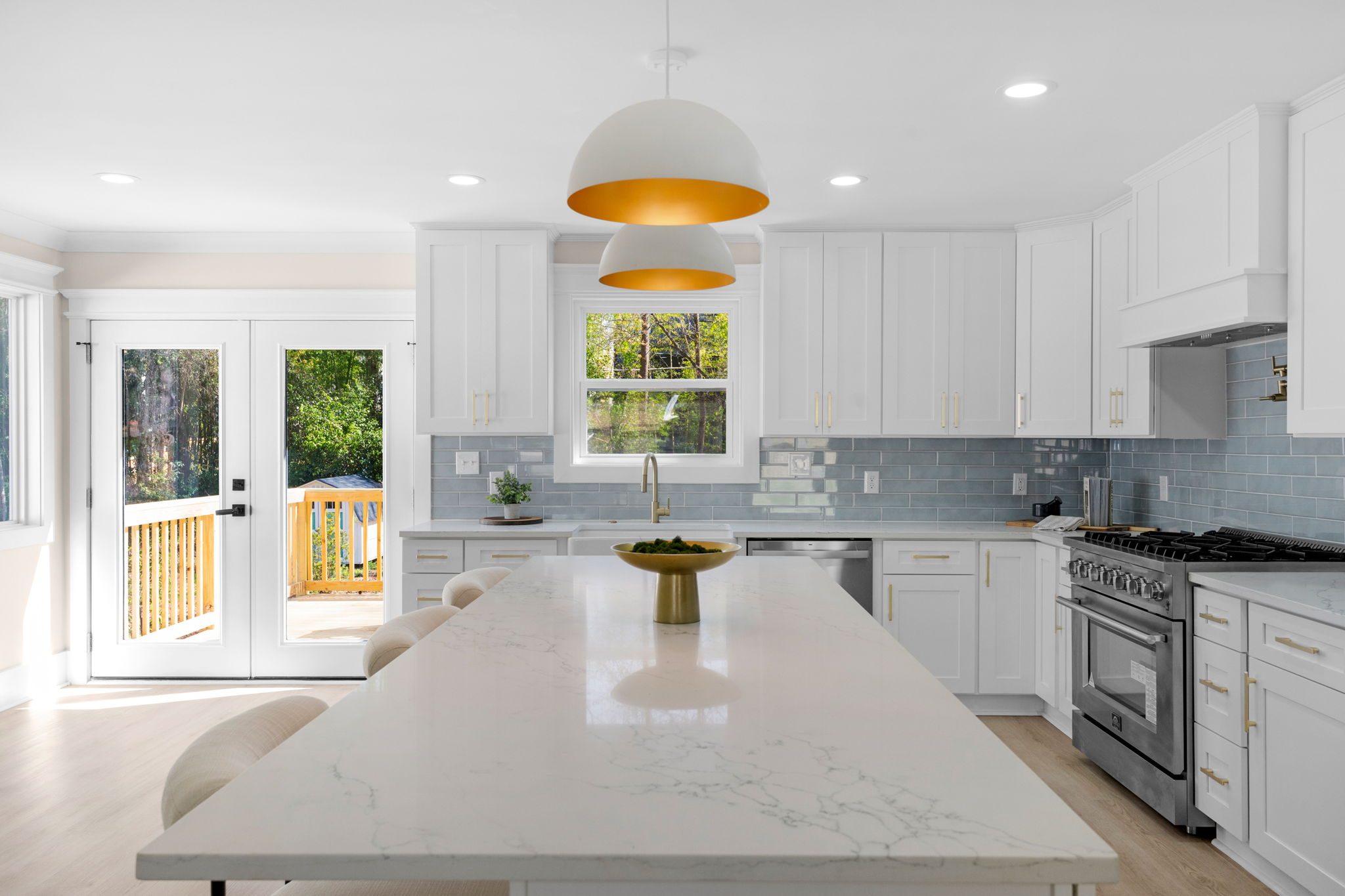 Renovated chef's kitchen with quartz island, white cabinetry, and brass pendant lighting — Wyanoke by Stillman Properties Charlotte NC