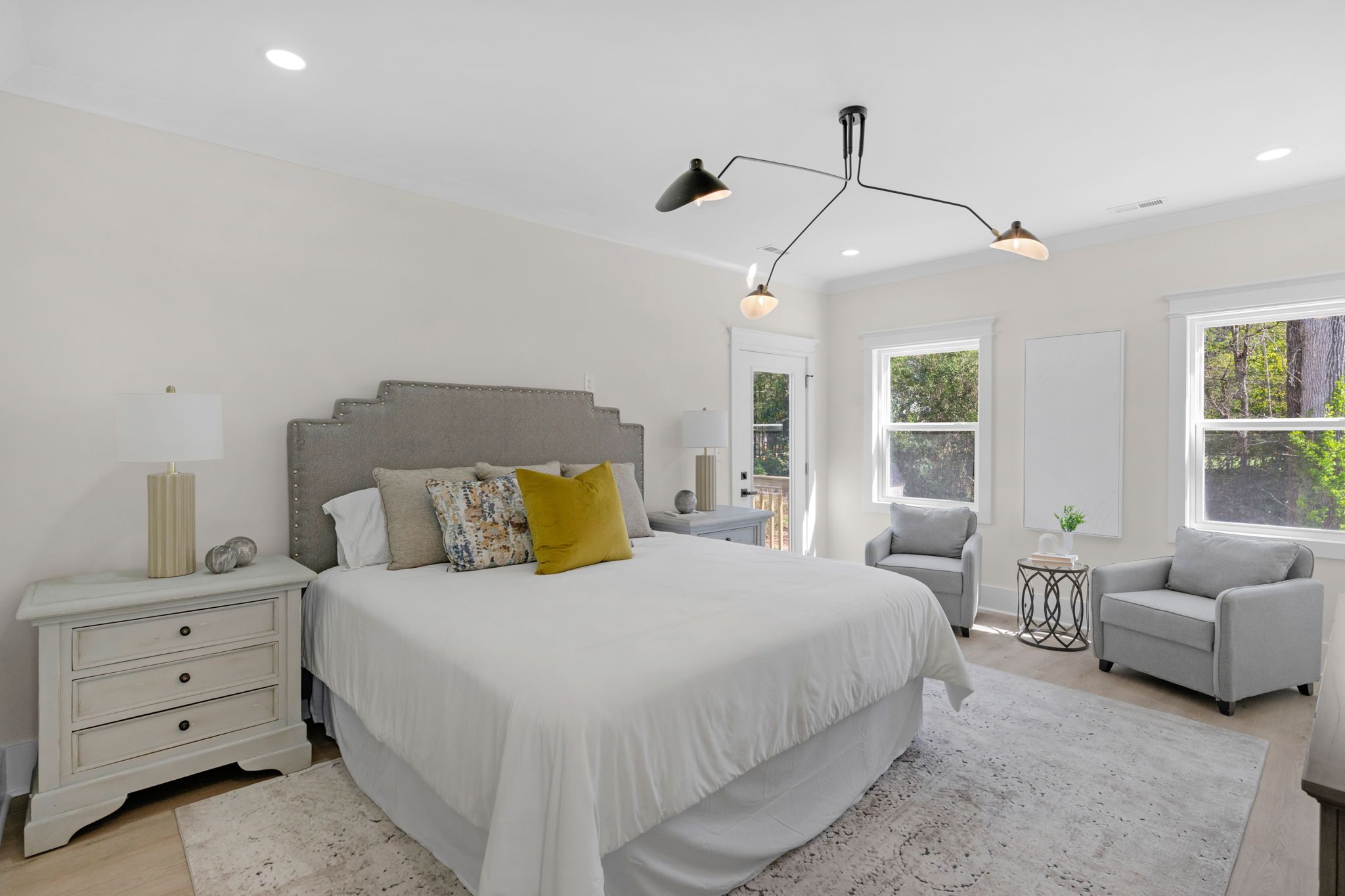 Primary bedroom with upholstered headboard and a window-side sitting area — Wyanoke by Stillman Properties Charlotte NC